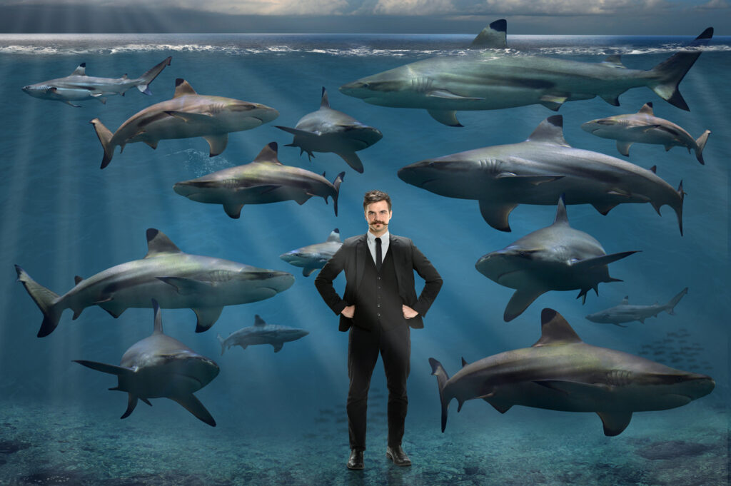 Confident young businessman surrounded by sharks underwater